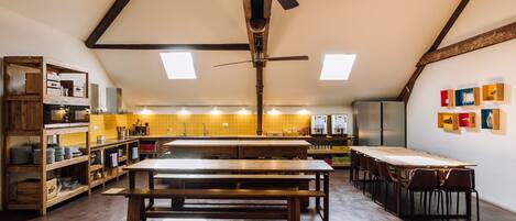 Una cocina estilo loft muy amplia, con techos altos, vigas a la vista y abundante luz natural.