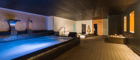 Een wellnessruimte met een jacuzzi, houten vloeren en een betegelde muur.