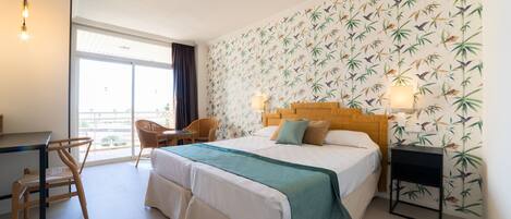 A hotel room with a large bed, a desk, a chair, and a window with a view.