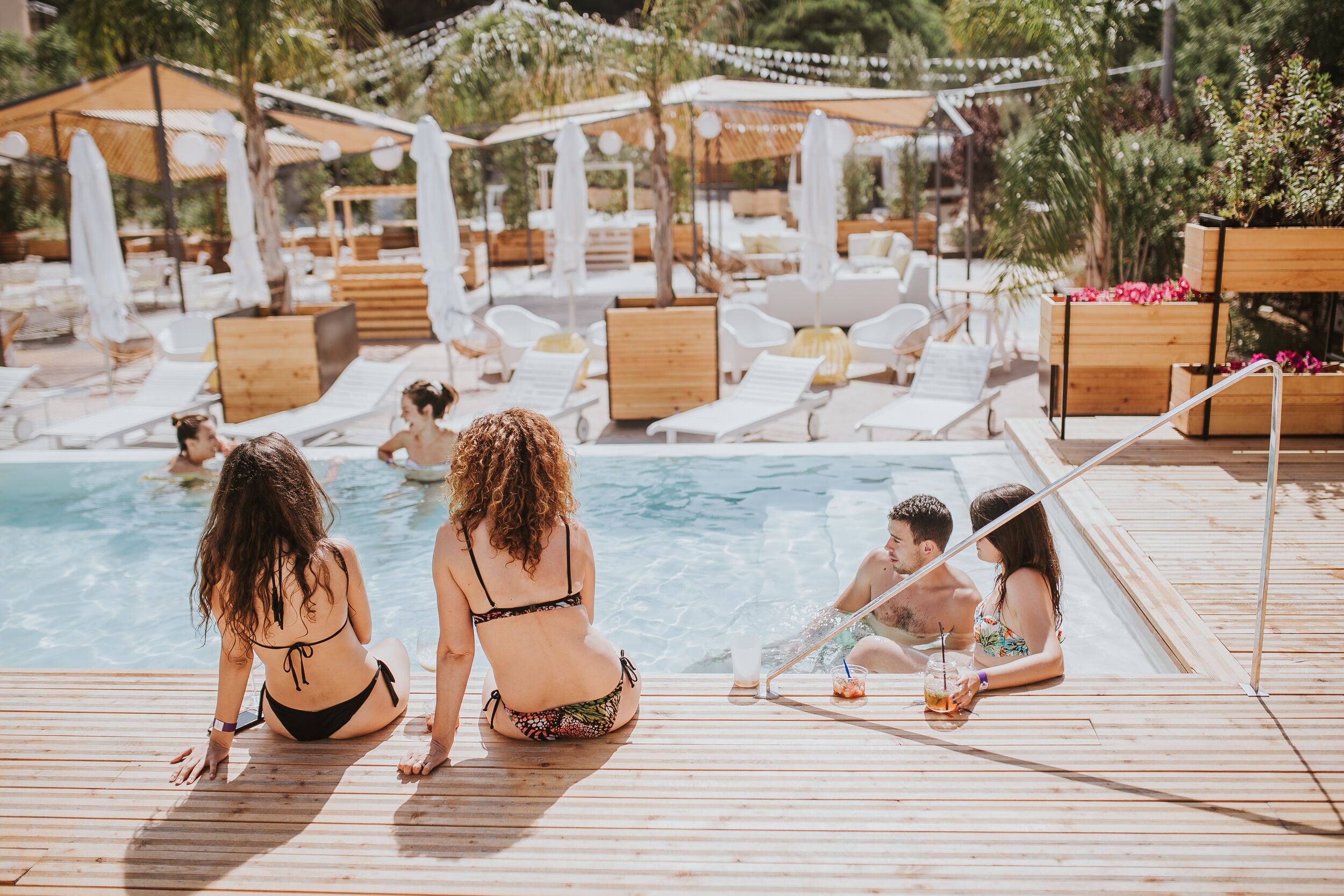 Una terraza de madera con sillones de descanso y zona de piscina.