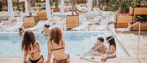 Una terraza de madera con sillones de descanso y zona de piscina.