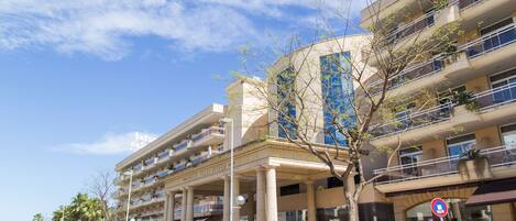 A multi-story hotel with a prominent entrance, balconies, and a clear sky.