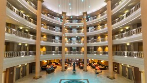 A multi-level hotel lobby with marble floors, a central fountain, and multiple balconies. - Hotel Palas Pineda (Vila-Seca)