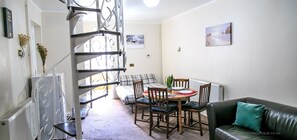 Un ambiente compatto con zona pranzo, divano e una scala.
