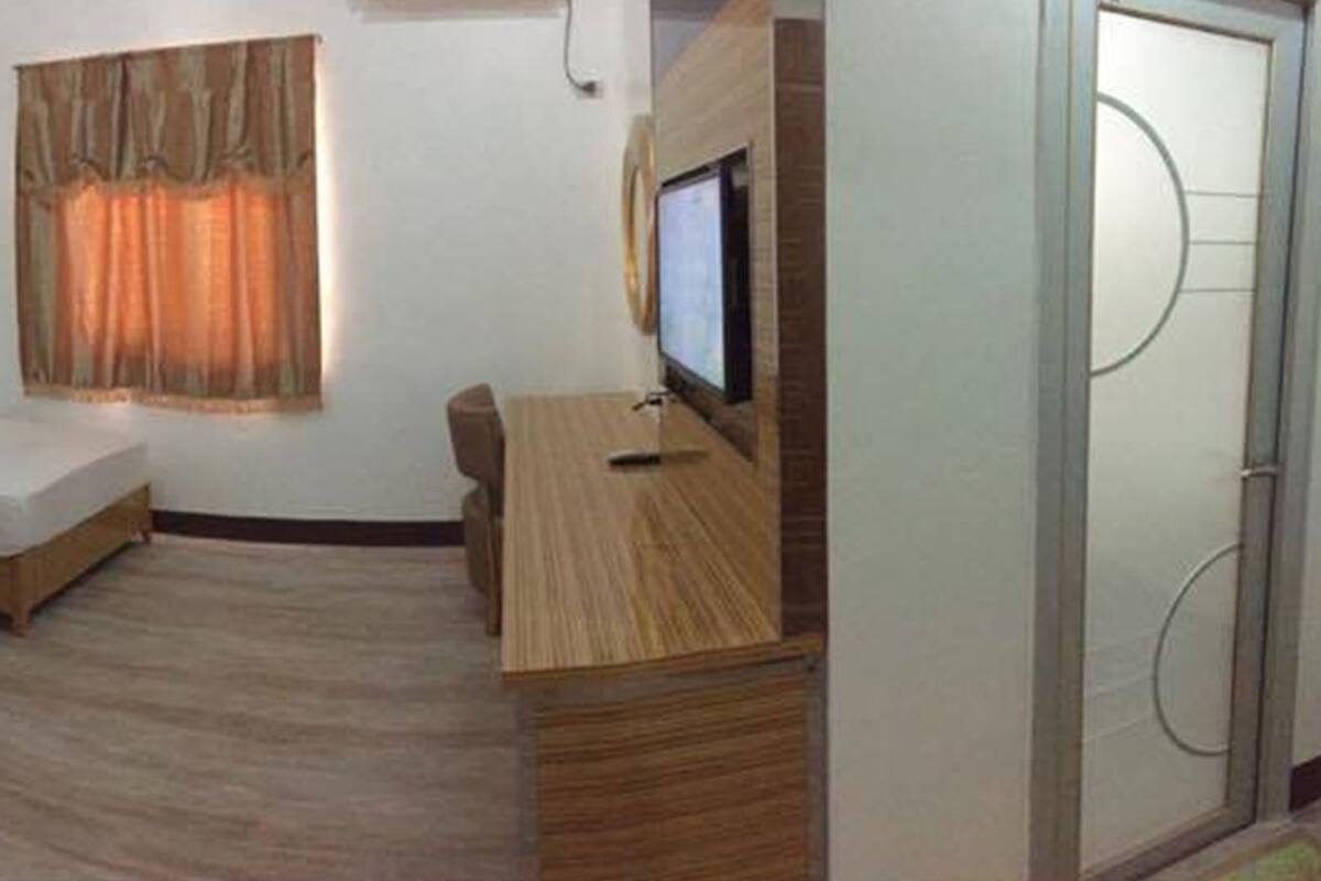 Hotelkamer met twee enkele bedden, een bureau, een televisie en een raam met gordijnen.