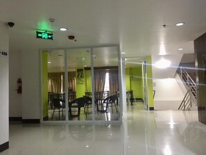 A hotel lobby with a glass partition, a staircase, and a green wall.
