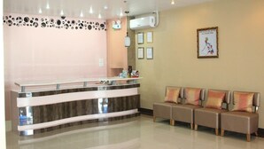 Un área de recepción con un mostrador moderno, un espacio de espera con asientos acolchados y una pared decorada con diplomas enmarcados.