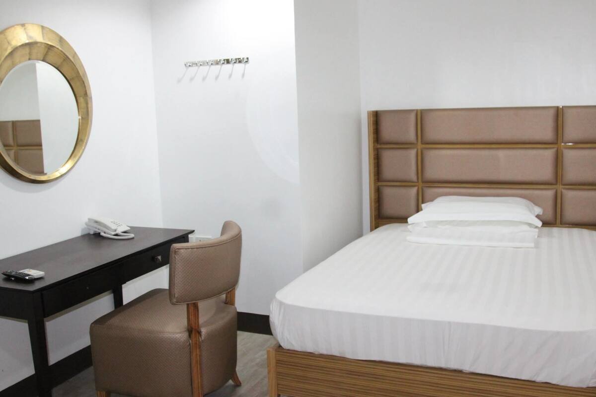 Een hotelkamer met een bed, een bureau, een stoel, een telefoon en een spiegel.