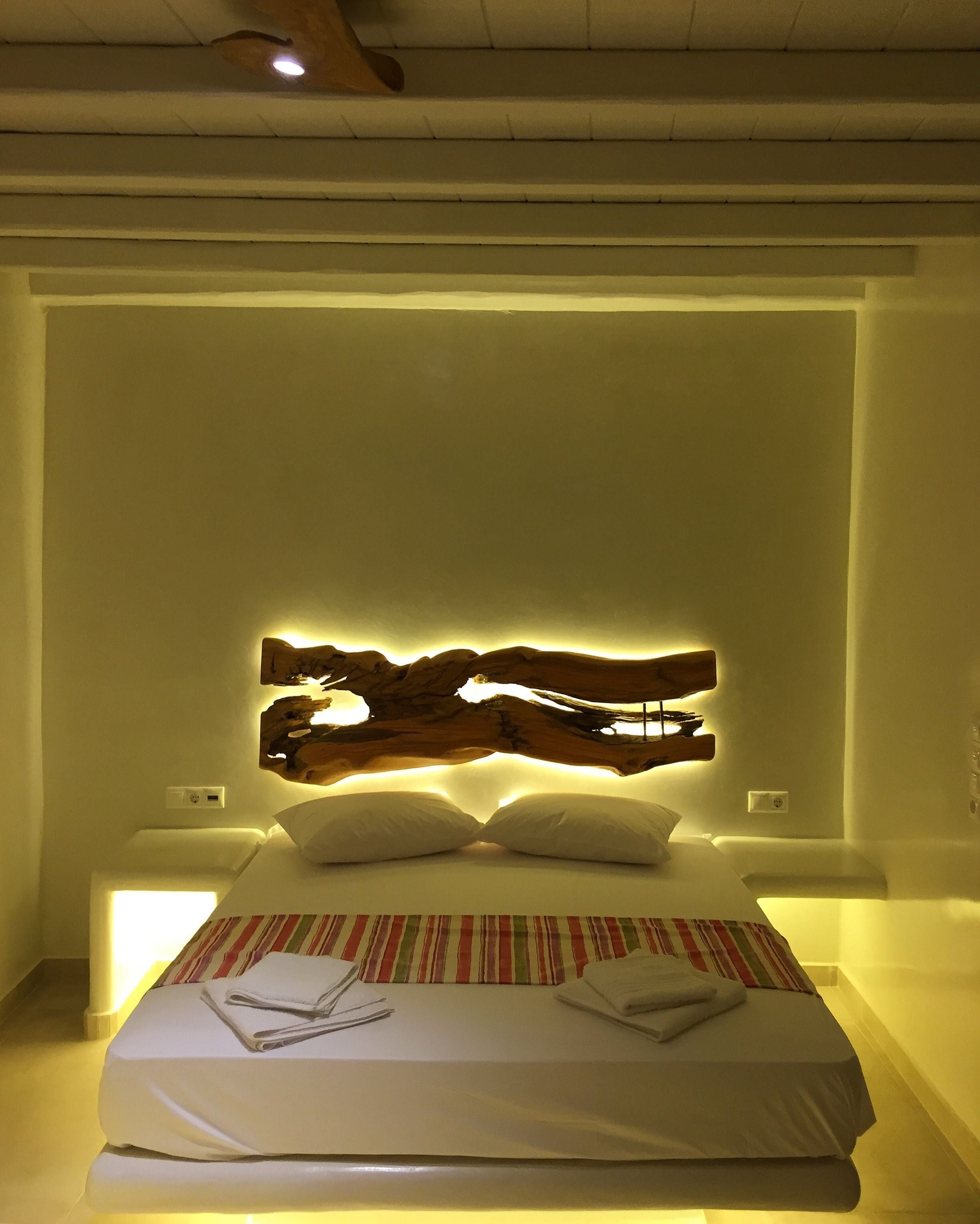 Una cama bien tendida con una colcha a rayas, un cabecero de madera y lámparas de noche.
