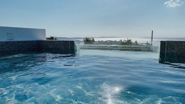 Une piscine aux eaux cristallines, offrant une vue sur des montagnes lointaines et un plan d’eau.