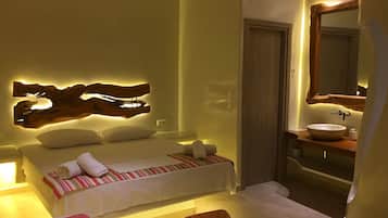 A hotel room with a bed, a wooden headboard, a bedside table, a mirror, and a bathroom with a sink.