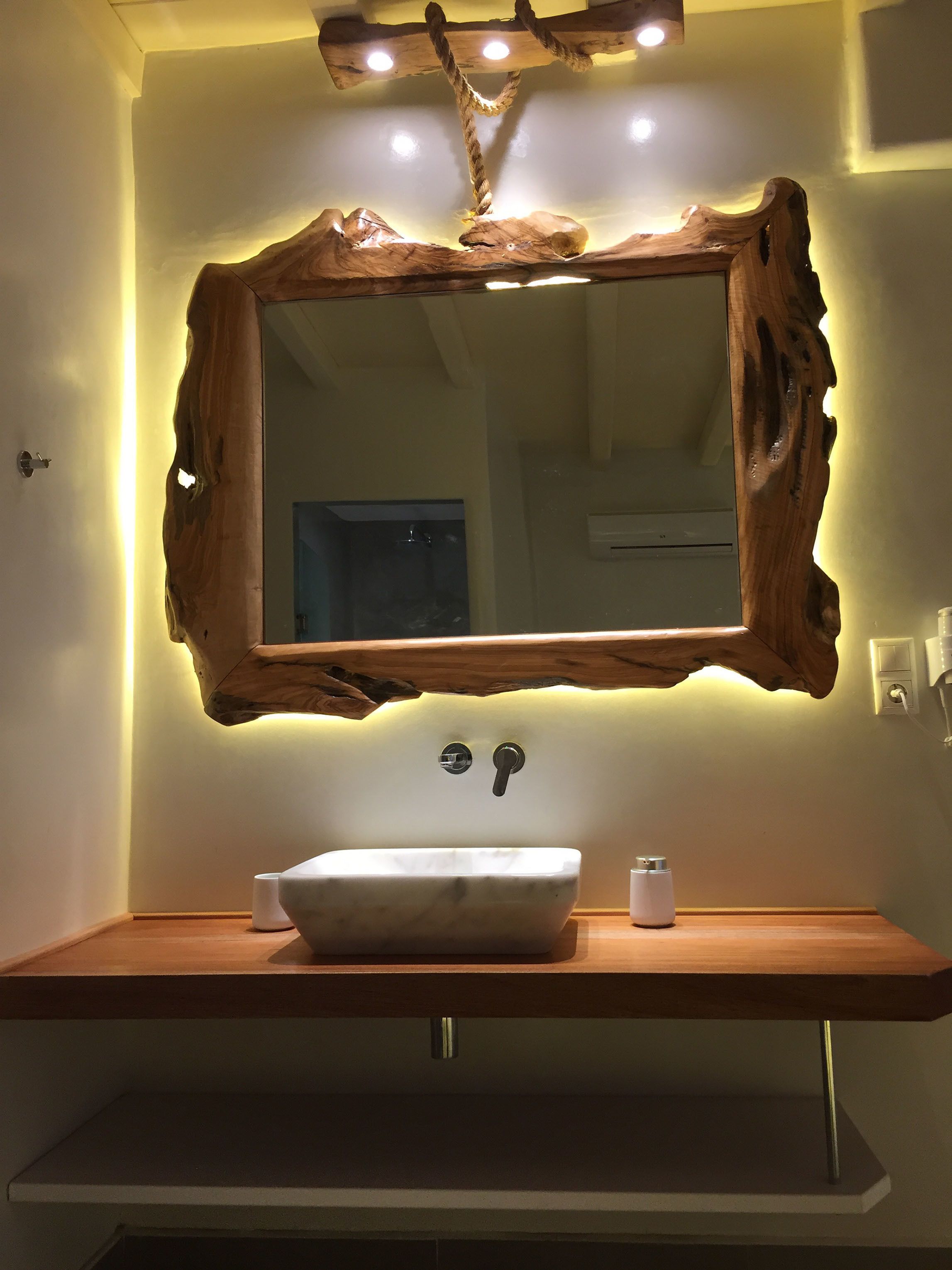 A bathroom with a rustic wooden mirror, a white sink, and a modern faucet.