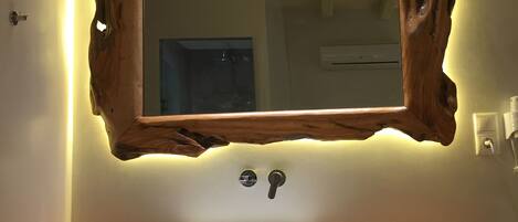 A bathroom with a rustic wooden mirror, a white sink, and a modern faucet.
