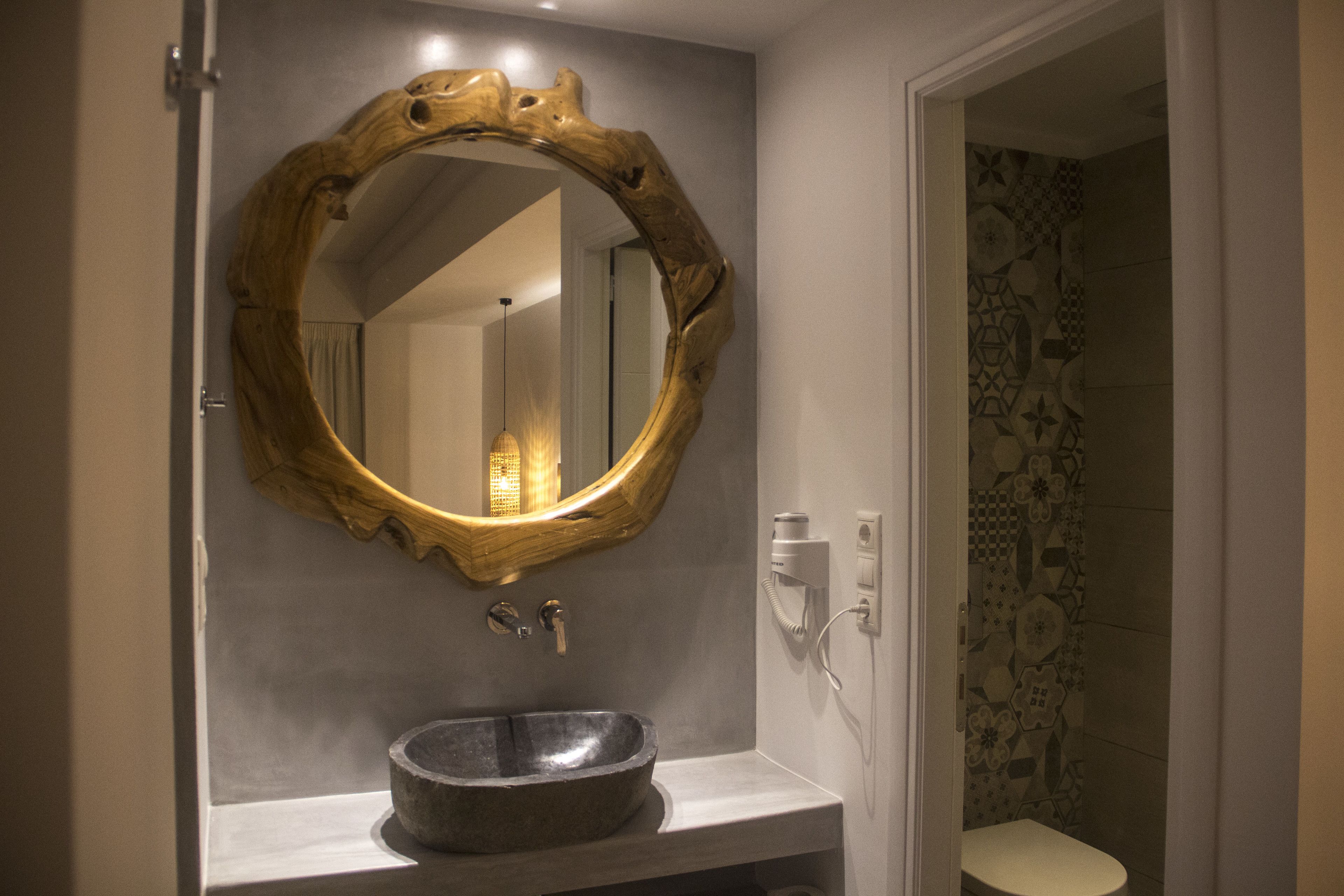 A bathroom with a large mirror, a stone sink, and a toilet.