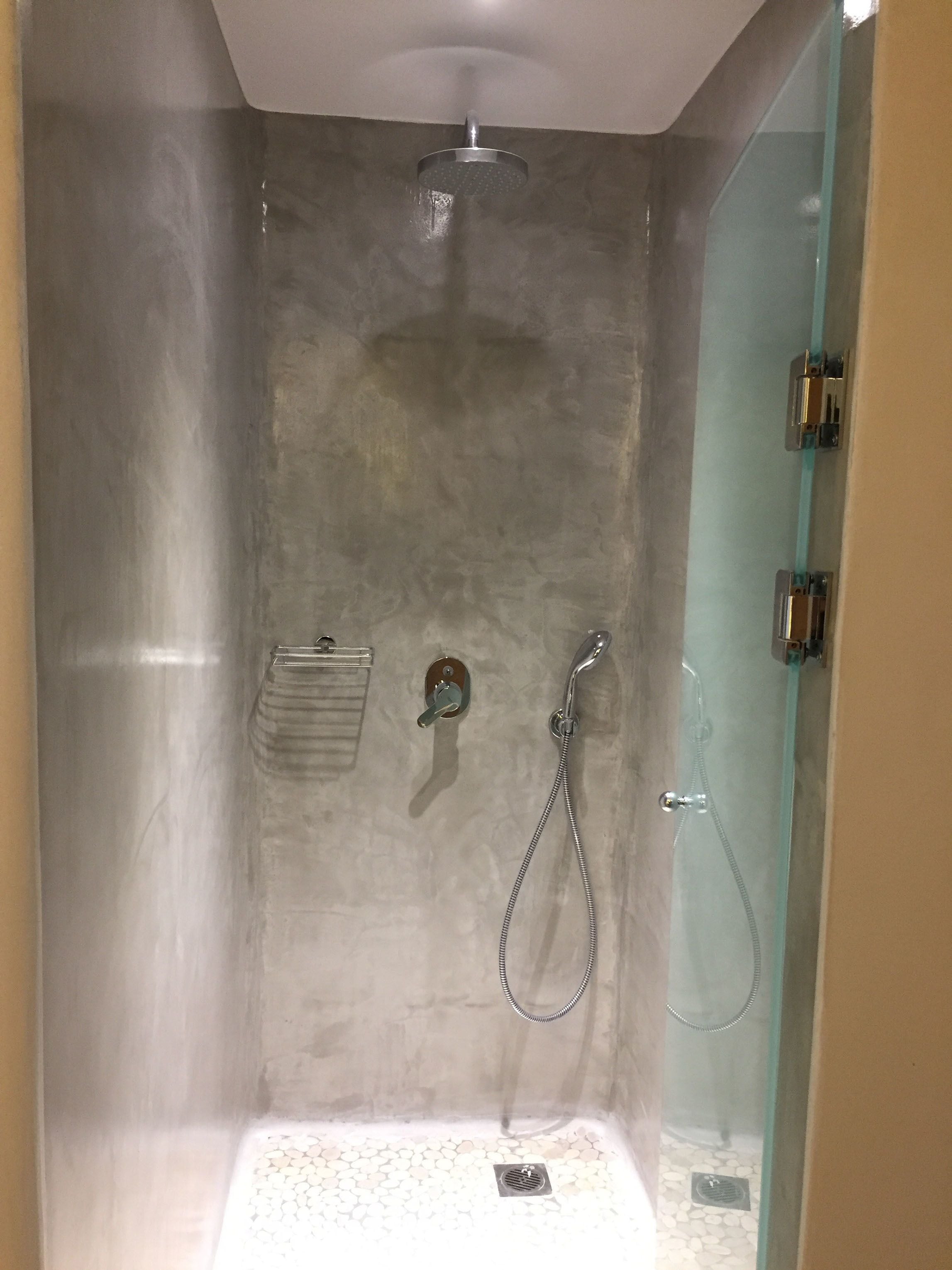 A walk-in shower with a glass door, a handheld showerhead, and a handheld faucet.