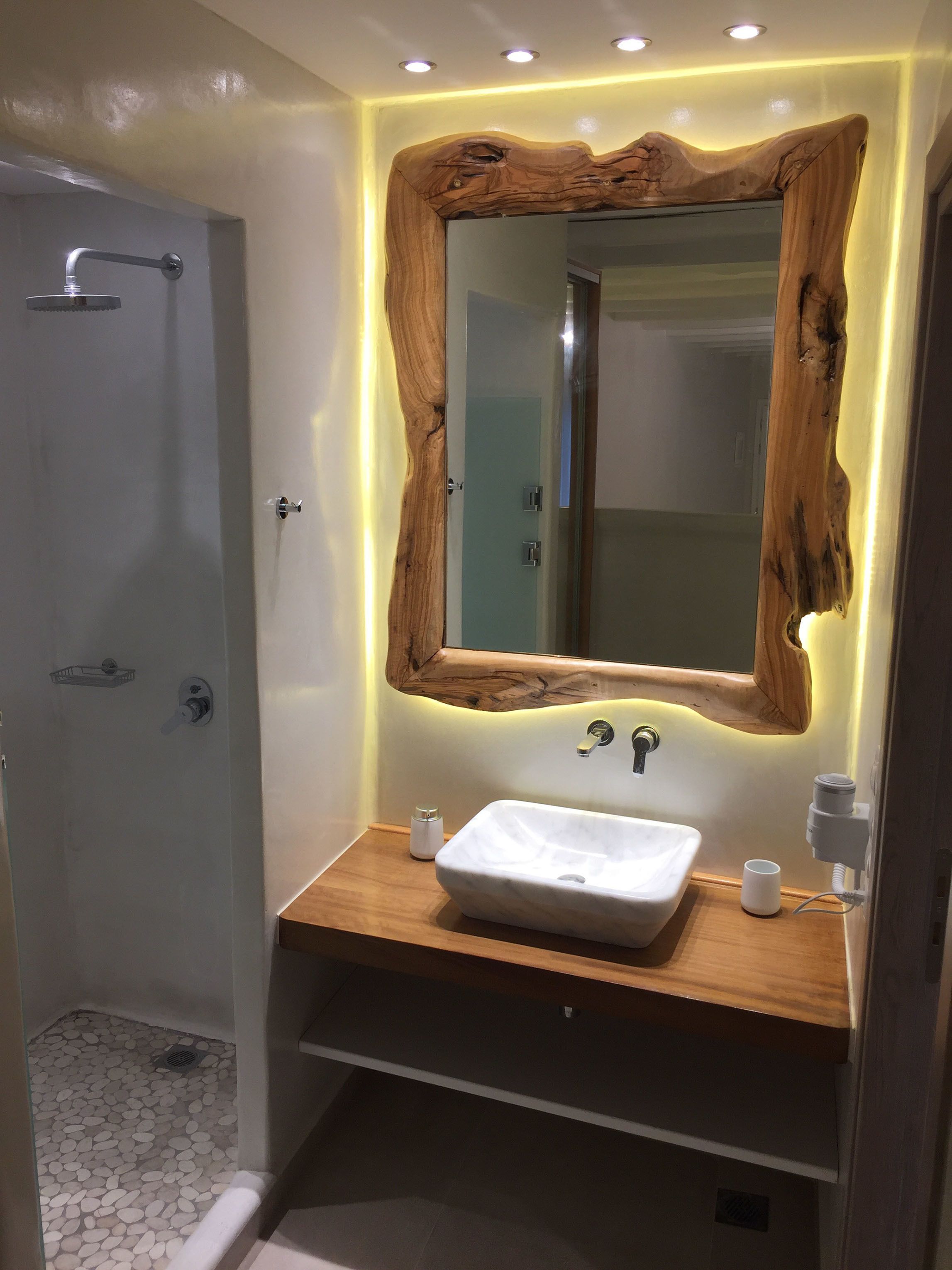 A bathroom with a wooden-framed mirror, a white sink, and a shower.