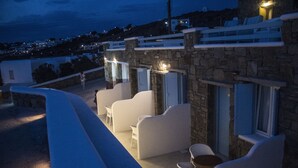 Un bâtiment en pierre doté de sièges extérieurs blancs et offrant une vue sur la ville en arrière-plan.