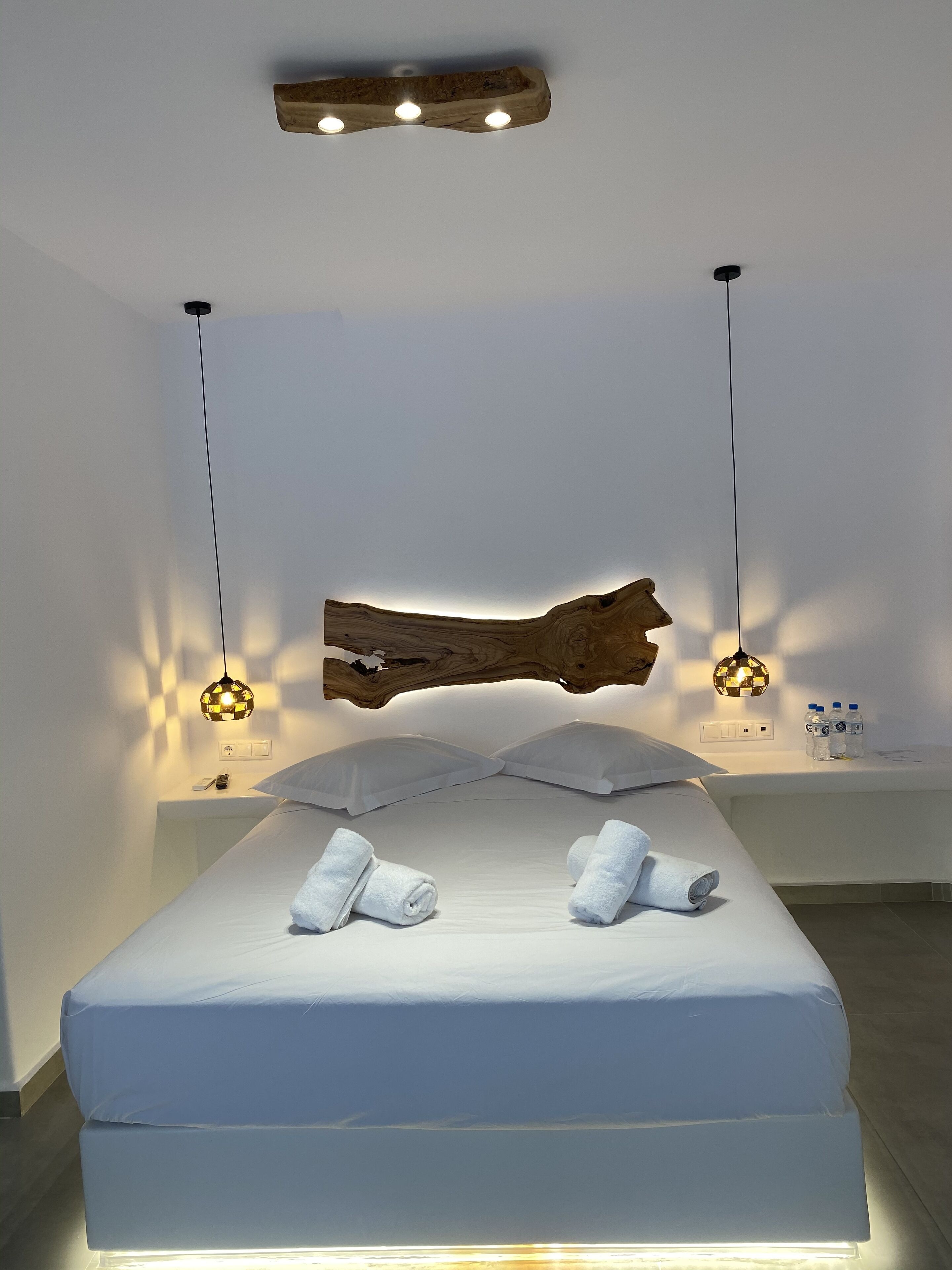 Un dormitorio moderno con una cama grande, ropa de cama blanca y dos mesitas de noche con lámparas.