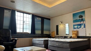 A hotel room with a large window, a sofa, a bed, a small table, and a patterned carpet. - HOTEL Galaxy (Isumi)