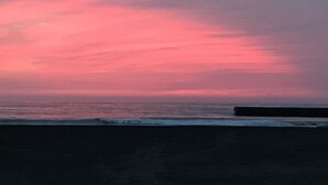 A beach with a sunset and a rocky outcrop in the distance. - HOTEL Galaxy (Isumi)