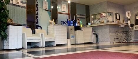 Un espace d’accueil comprenant un comptoir d’enregistrement, un coin salon et un tapis rouge.