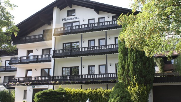 A multi-story hotel with balconies and a garden area. - Hotel Vitalesca (Neuschoenau)