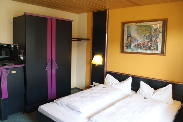 A hotel room with a bed, a desk, a wardrobe, and a painting on the wall. - Hotel Vitalesca (Neuschoenau)