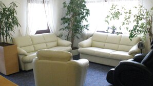 A living room with two cream-colored sofas, a small armchair, and a potted plant. - Hotel Vitalesca (Neuschoenau)