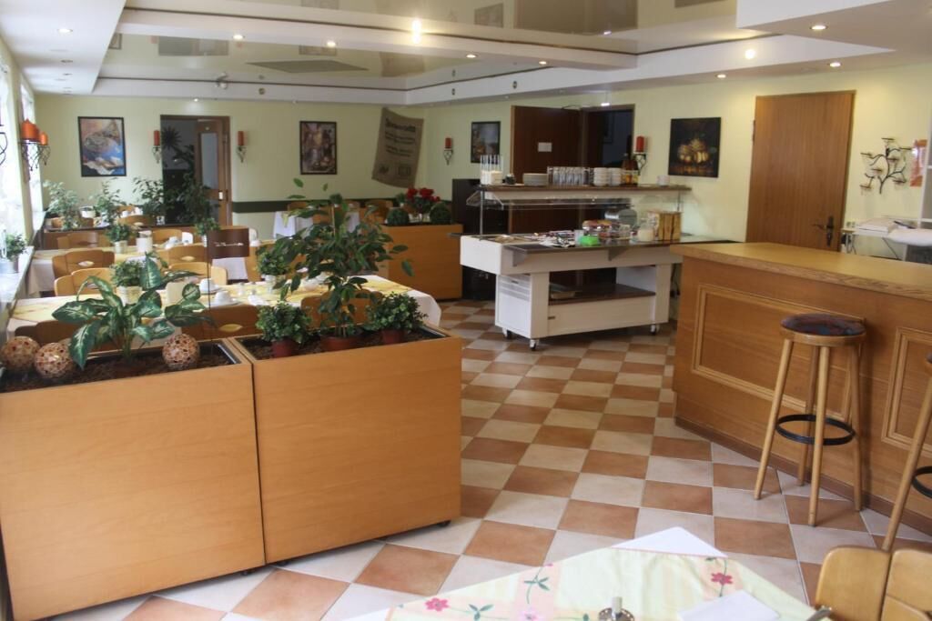 Rebedor d'hotel amb sòl a escacs, mostrador de recepció de fusta i diverses plantes en testos.