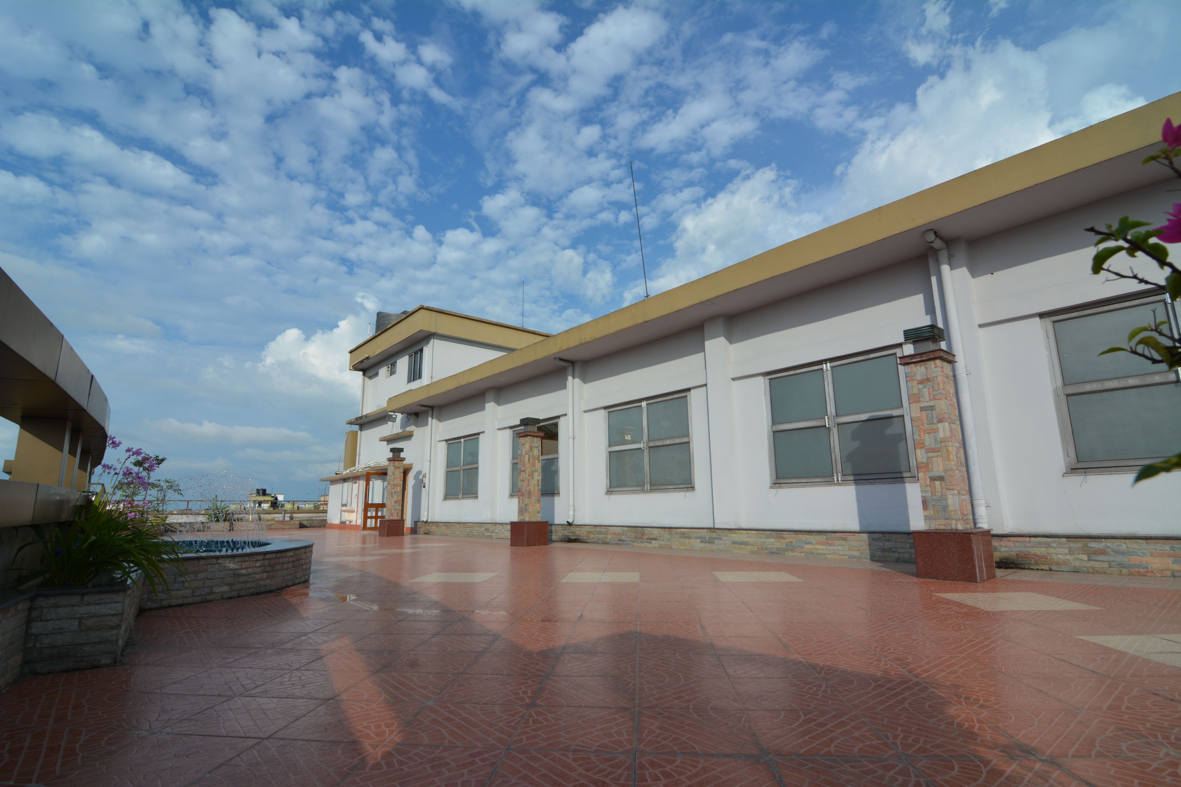 A building with a flat roof, large windows, and a tiled floor.