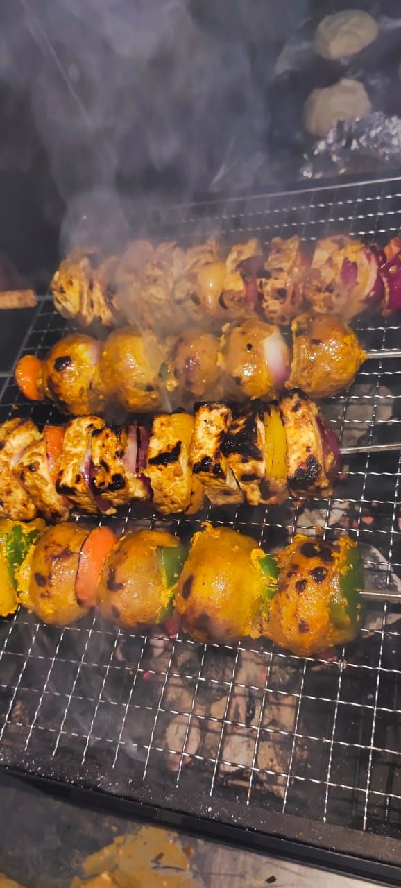 Una parrilla con diversos pinchos de carne y verduras.