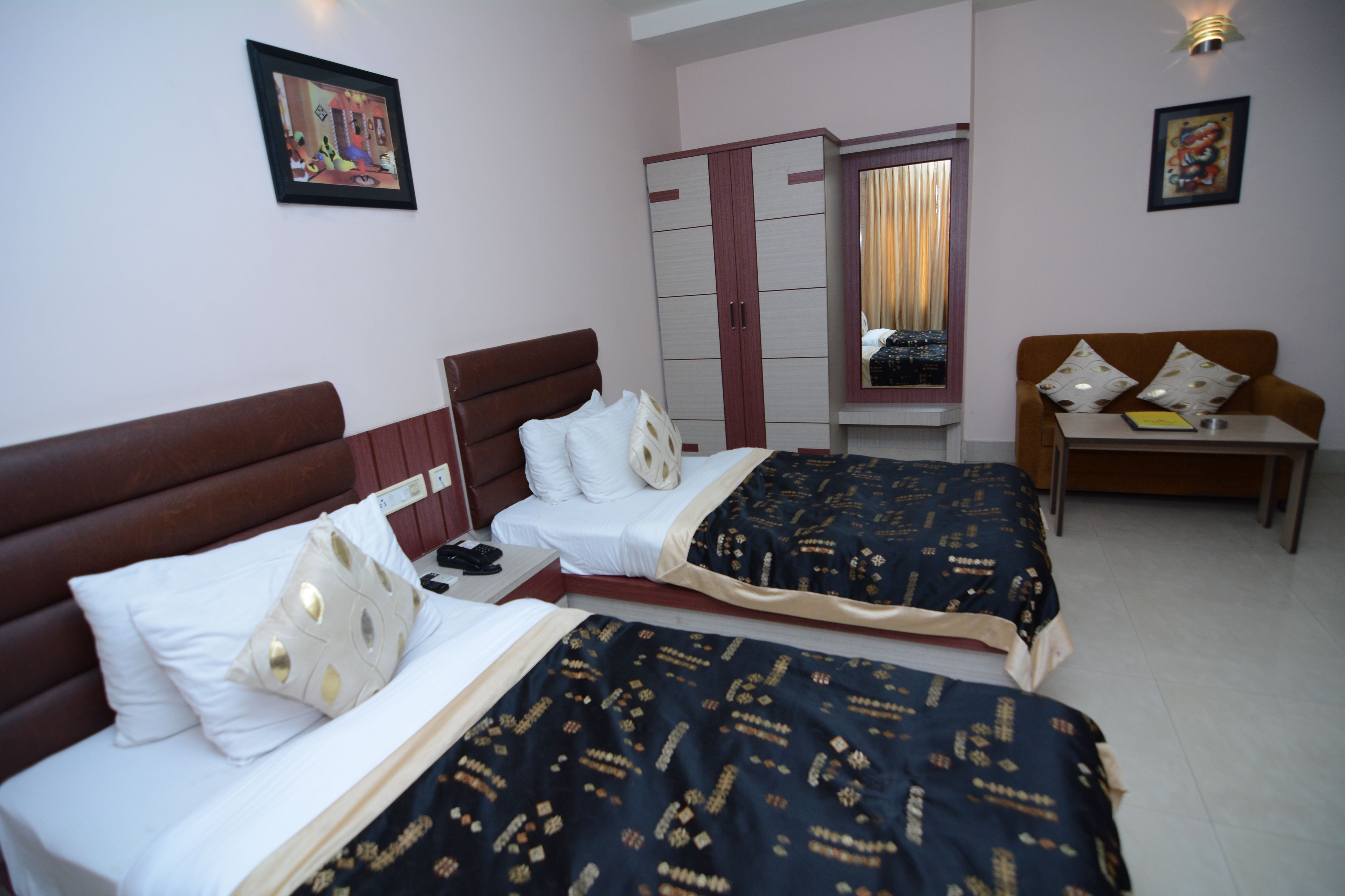 A hotel room with two beds, a wardrobe, a desk, and a sofa.