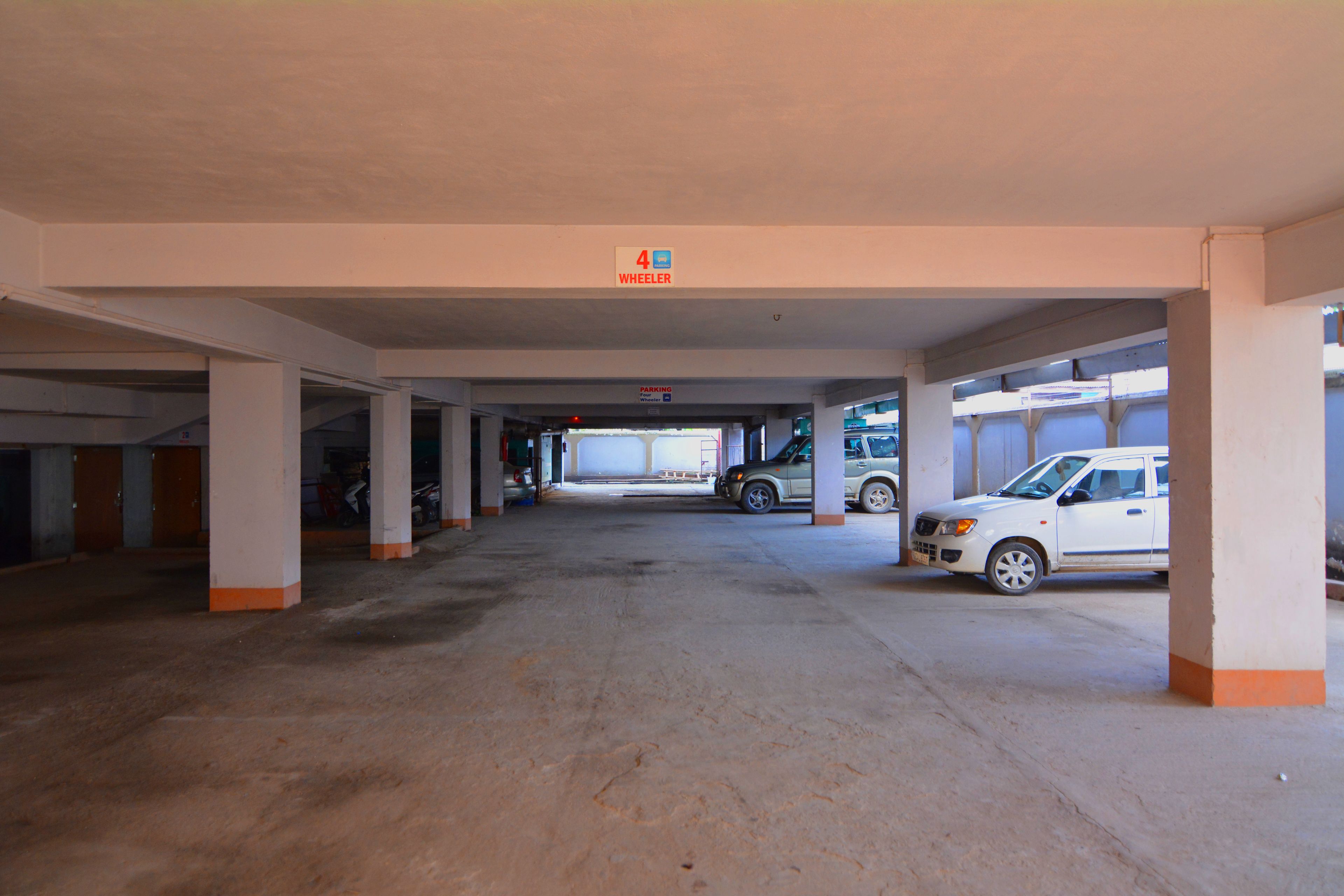 Een parkeergarage met meerdere verdiepingen, betonnen pilaren en enkele geparkeerde auto's.