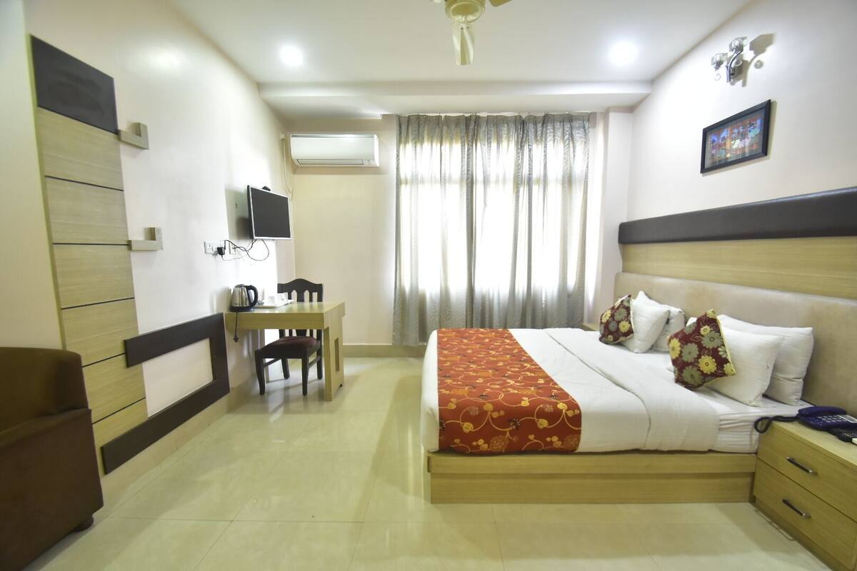 Quarto de hotel com cama, mesa de cabeceira e escrivaninha com cadeira.