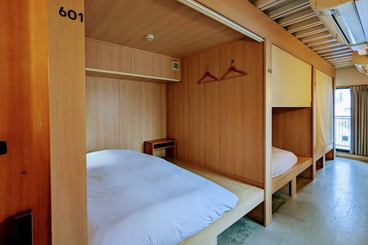 Habitación pequeña con literas, paredes de madera y una mesita de noche.