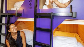 A bunk bed room with a purple wall, a wooden headboard, and a white mattress.