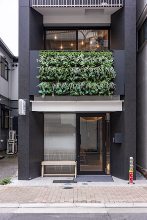 Ein modernes Gebäude mit vertikalem Garten, geschlossenem Eingang und einer Bank davor.