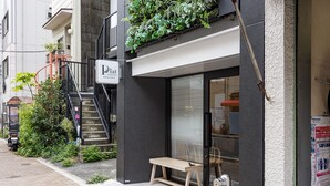 A building with a black facade, a wooden bench outside, and a staircase with greenery.