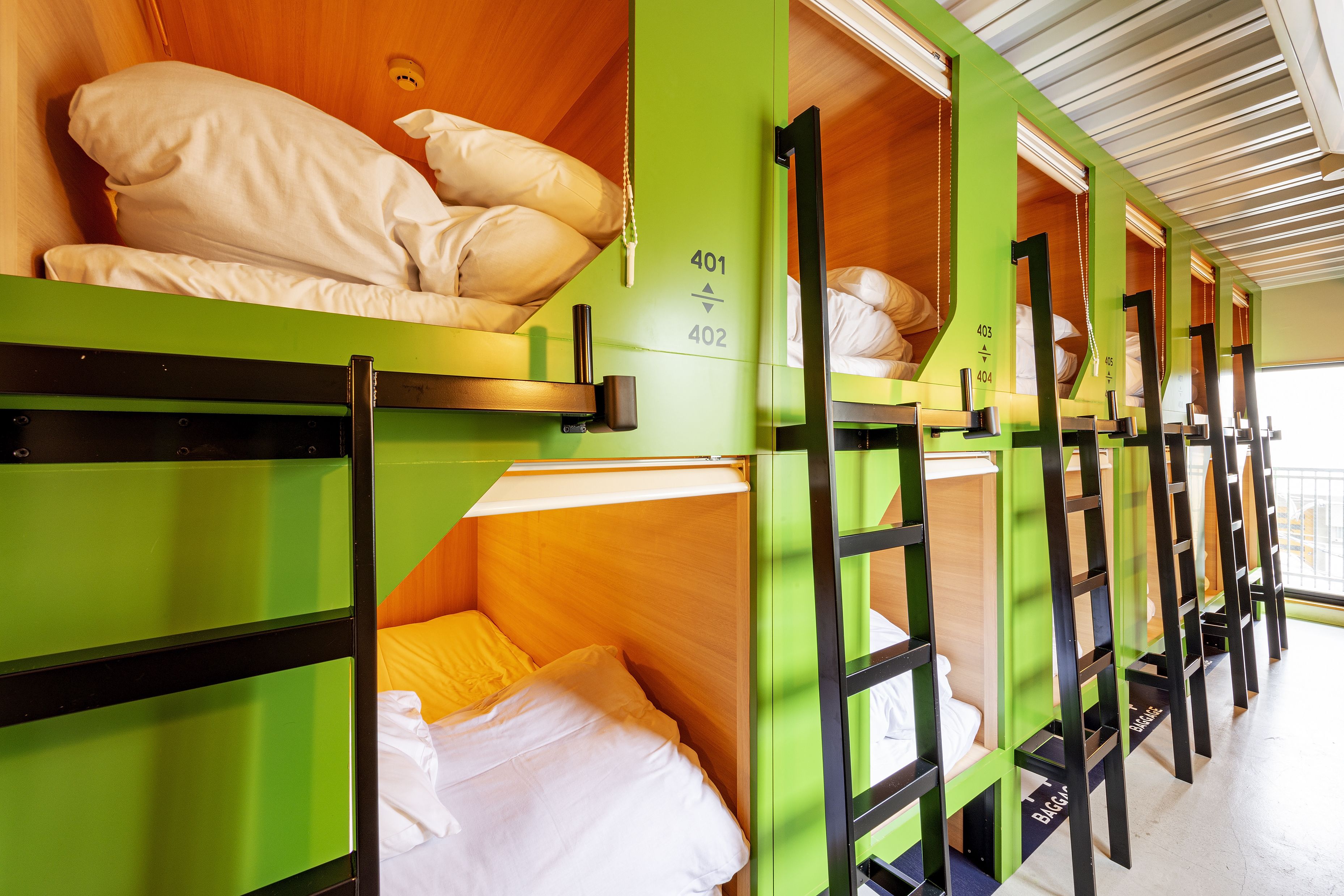 Bunk beds with numbers 401 and 402, wooden headboards, and a window with blinds.
