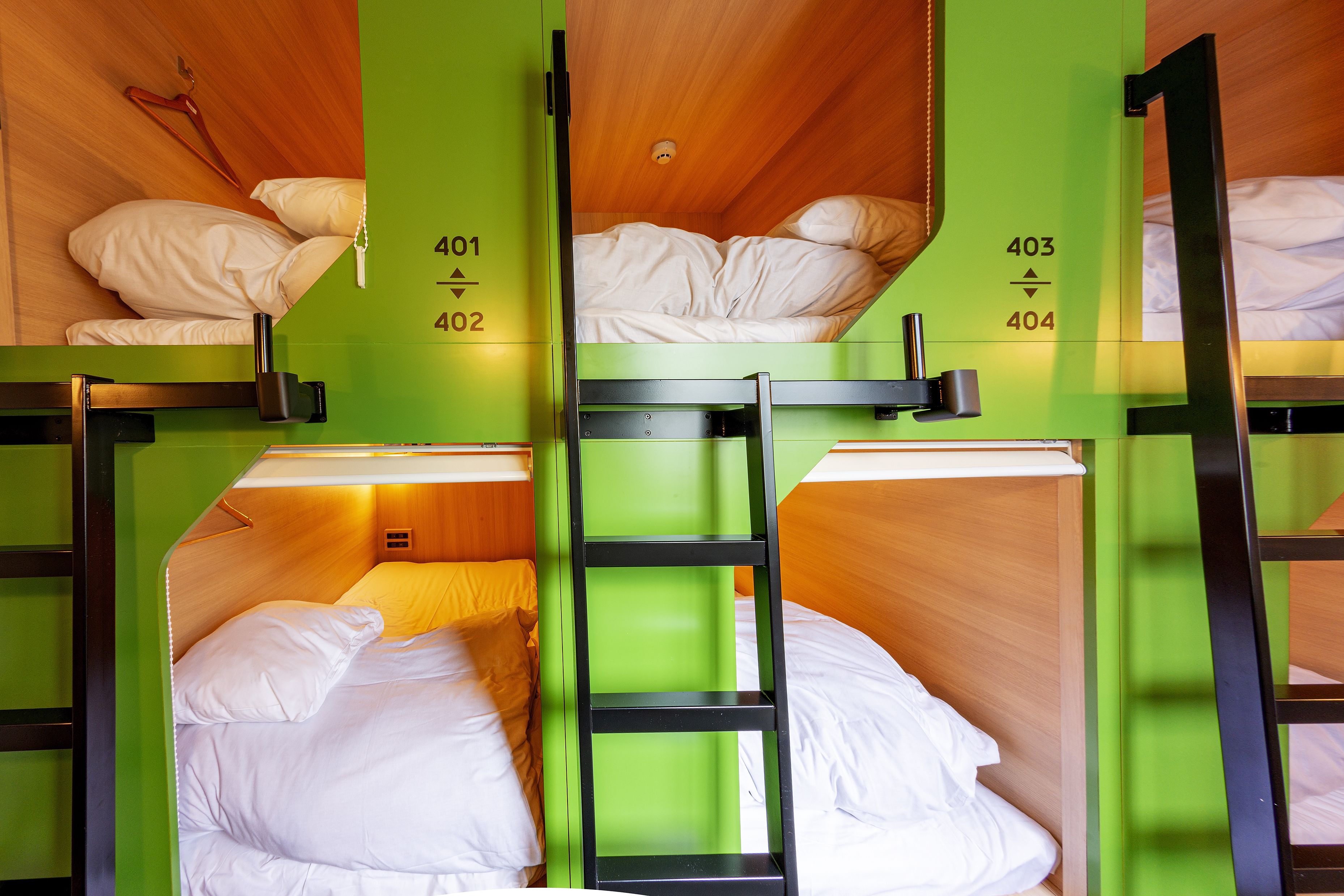 Ein Schlafzimmer mit Etagenbetten, grünen Wänden und nummerierten Betten.