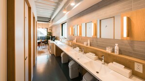 A modern bathroom with multiple sinks, a long counter, and a large mirror.