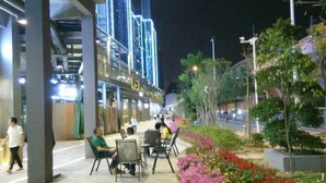 An outdoor seating area with tables and chairs, surrounded by flower beds with pink and red flowers. - One Flight Apartment Bao'an Branch (Shenzhen)