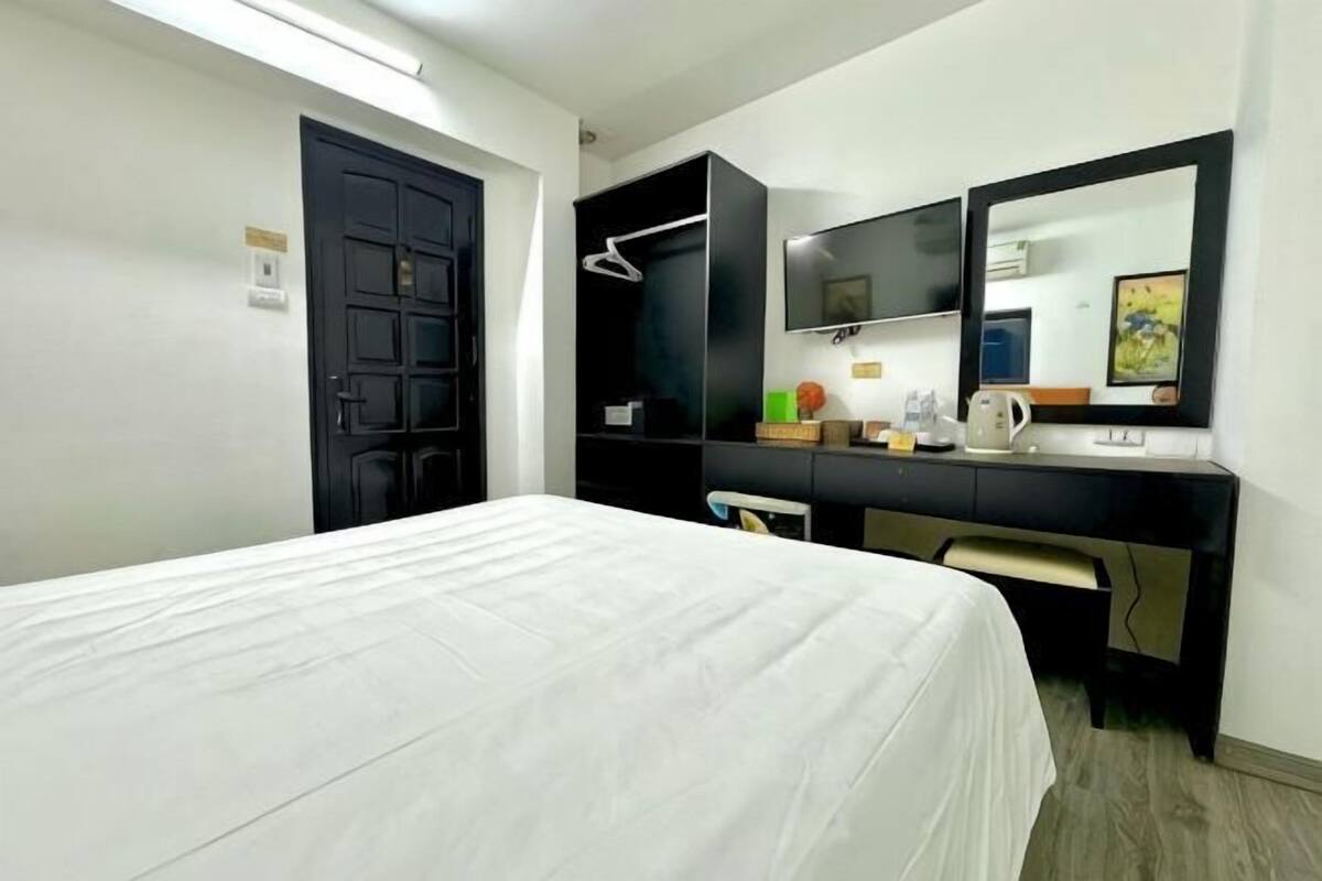 Une chambre d’hôtel comprenant un lit, un bureau avec un ordinateur, une télévision et une armoire.