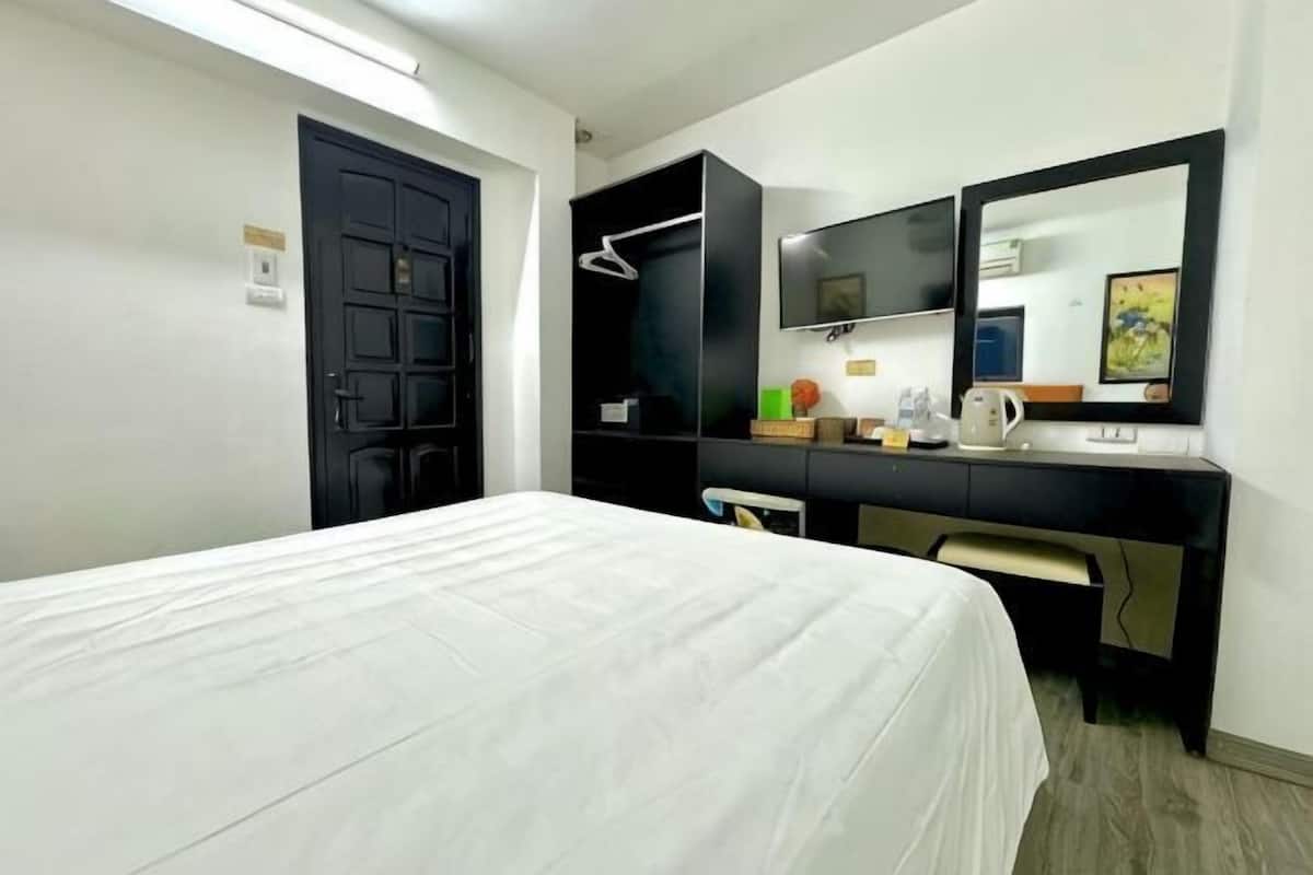 Une chambre d’hôtel comprenant un lit, un bureau avec un ordinateur, une télévision et une armoire.