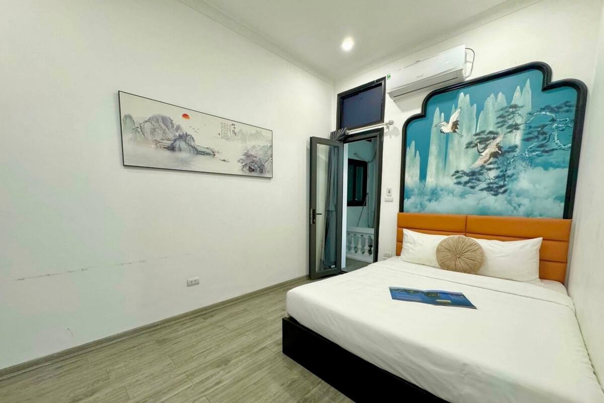 Une chambre d’hôtel avec un lit, un tableau, un appareil de climatisation et une fenêtre.