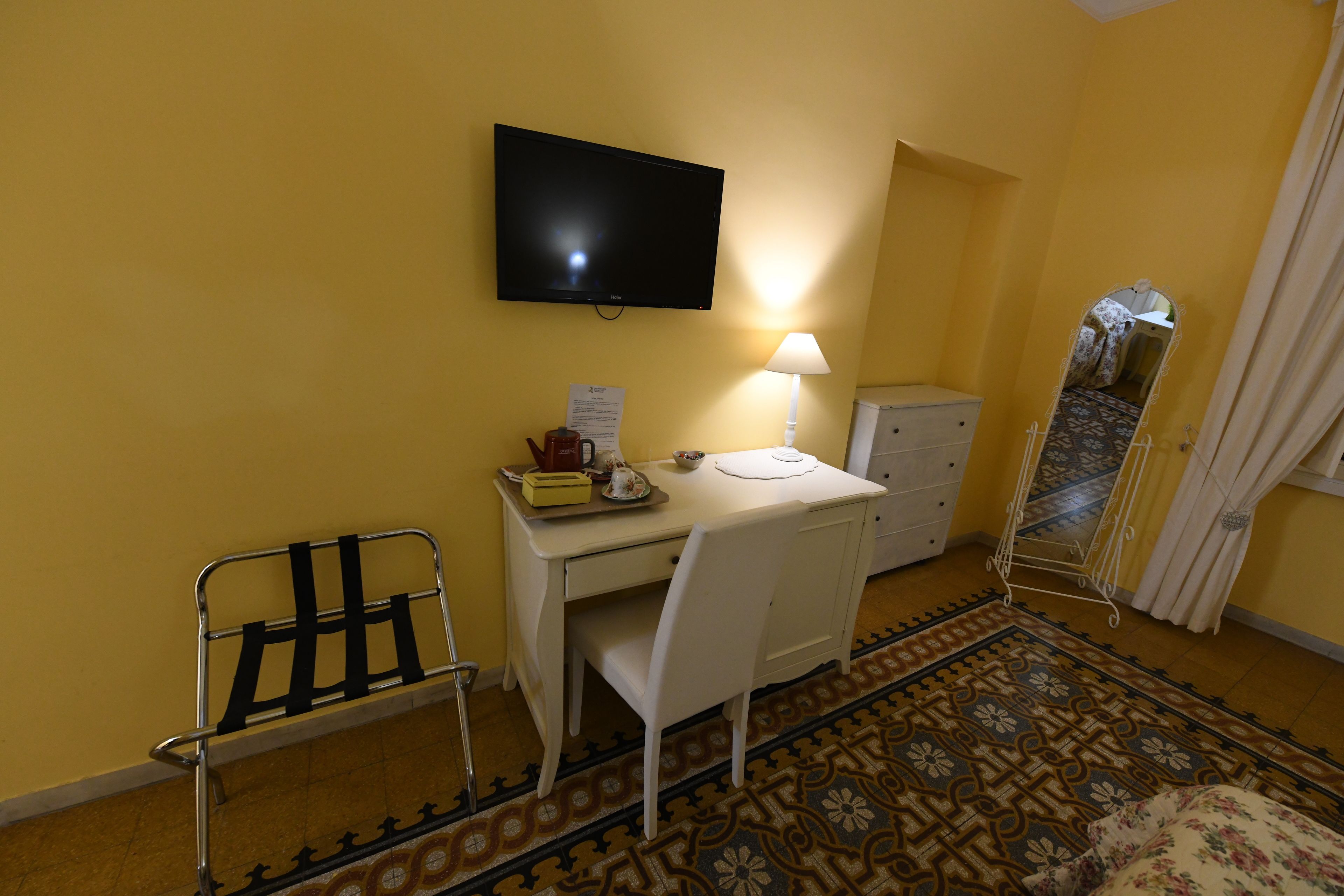 Une pièce comprenant un bureau, une chaise, une télévision, une lampe et un miroir.