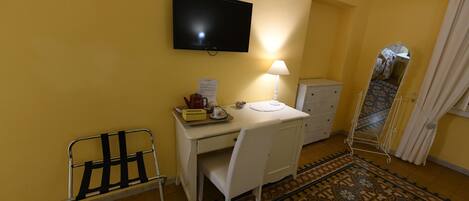 Une pièce comprenant un bureau, une chaise, une télévision, une lampe et un miroir.