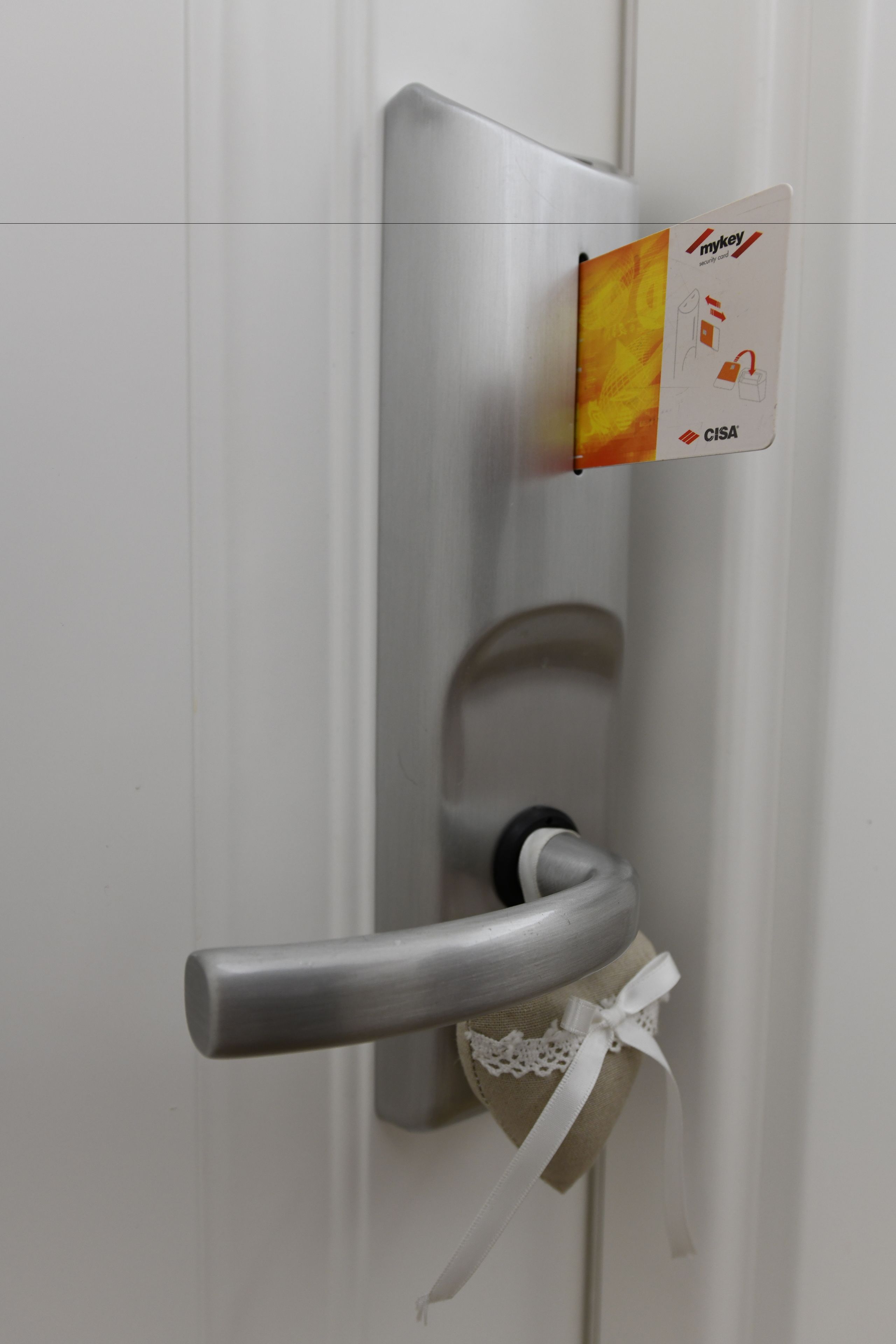 A door with a metallic handle and a card holder displaying a key card.