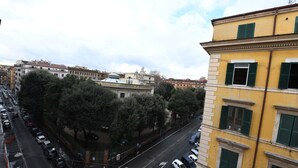 A city street with parked cars, trees, and buildings. - Buonanotte Roma 2 (Rome)