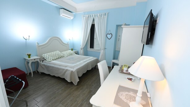 A bedroom with a bed, bedside table, lamp, and a TV mounted on the wall. - Buonanotte Roma 2 (Rome)